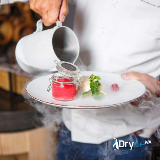 a waiter is pouring dry ice from a small jug onto a dessert